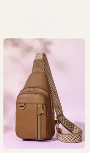Detail of brown litchi leather sling bag showing headphone port and woven strap