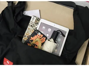 Detail shot of large capacity black shoulder bag showing interior storage for iPad and umbrella