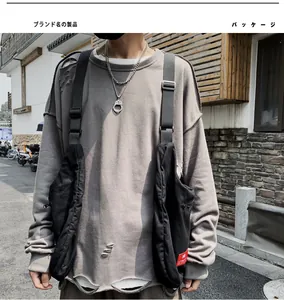 Detail of grey oversized sweatshirt with distressed holes and black functional vest bag