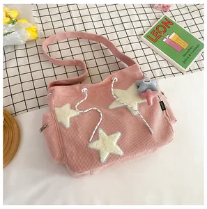 Détail d'un sac cabas en velours côtelé rose avec écussons étoiles et poche zippée latérale