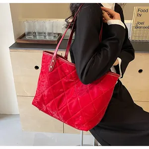 Detail of red quilted tote bag showing nylon satin texture and leather shoulder straps