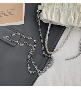 Detail of white pleated cloud bag featuring sparkling rhinestone handle and silver chain