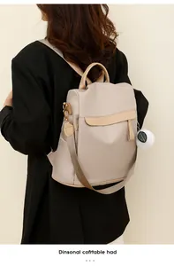 Détail du sac à dos en nylon beige clair avec fermeture antivol et breloque en peluche
