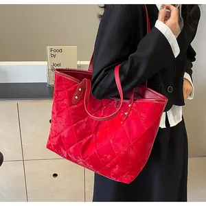 Detail of red quilted tote bag with diamond stitching shown on model shoulder