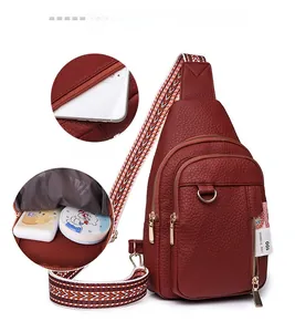 Detail of red pebbled leather chest bag showing multiple compartments and wide woven strap