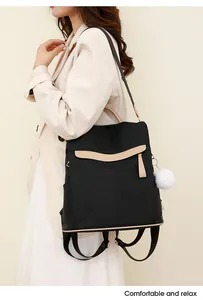 Détail d'un sac à dos en nylon noir avec garniture en cuir beige et pompon blanc doux