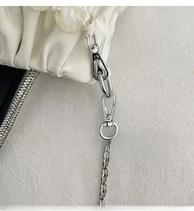 Detail of silver spring hook and metal chain on white pleated leather shoulder bag