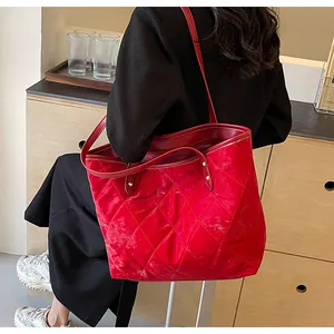 Close-up of red quilted tote bag with diamond stitching and golden rivet details on the strap