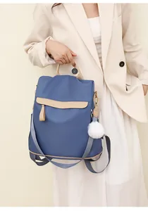 Détail d'un sac à dos en nylon bleu marine avec accents en cuir beige et pompon blanc