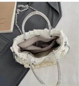 Detail view of white pleated handbag with rhinestone handle and internal compartments