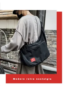 Detail of a black canvas crossbody bag with red logo tag and front zipper closure