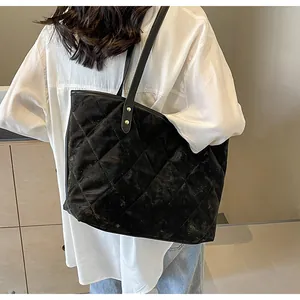Detail of black quilted velvet tote bag showing large diamond stitching and leather straps