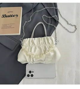 Close-up of white pleated cloud bag with translucent beads and silver chain strap