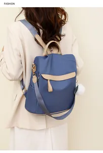 Détail du sac à dos en nylon bleu avec accents en cuir beige et pendentif en peluche blanche