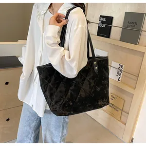 Close-up of black quilted velvet tote bag with gold rivets shown on a female model