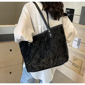 Close-up of black quilted tote bag with diamond stitching and golden rivet details