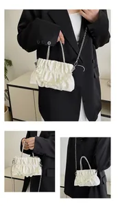 Detailed view of pearl white pleated bag with rhinestone handle and bead decoration