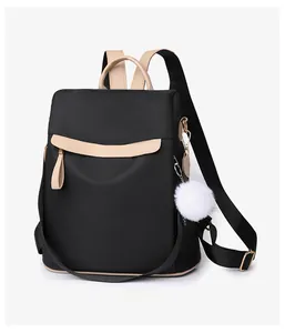 Détail du sac à dos noir et beige avec zips dorés et breloque pompon blanc soyeux