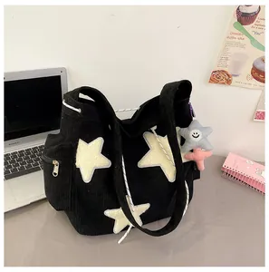 Détail d'un sac cabas en velours côtelé noir avec patchs étoiles et pendentif peluche