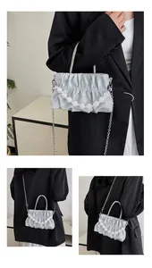 Detail of pleated cloud handbag with white bead chain and metallic shoulder strap