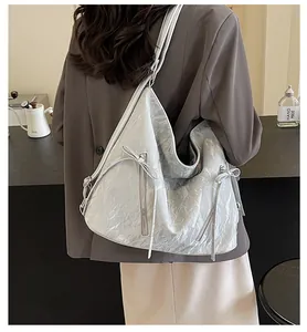 Detail of silver metallic hobo bag featuring long ribbon bows and wrinkled texture