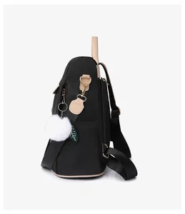 Vue latérale du grand sac à dos noir avec détails dorés et pompon décoratif doux