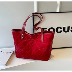 Close-up of red quilted tote bag with diamond stitching and gold metal rivets