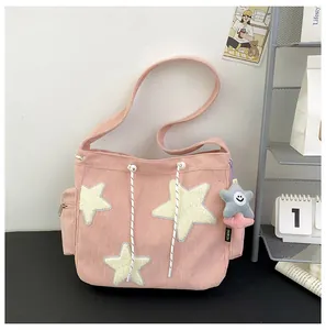Détail du sac cabas en velours rose avec patchs d'étoiles et charm étoile souriante