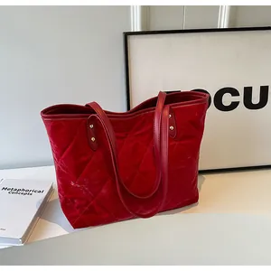 Detail of red quilted tote bag featuring glossy texture and golden metal rivets