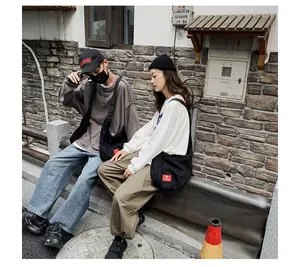 Close-up of the black canvas crossbody bag with brand logo shown in a street lifestyle setting