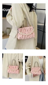 Macro detail of pink ruched cloud bag with rhinestone handle and pearl bead strap