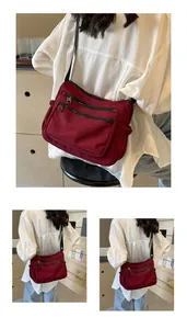 Detailed close-up of dark red nylon crossbody bag with multi-zipper pocket design