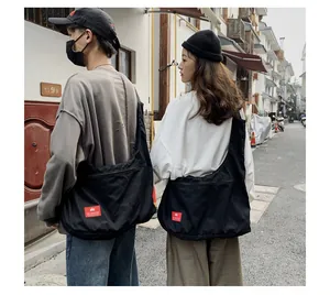 Detail of black canvas tote bag with iconic red logo label worn in urban street setting