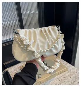 Detail of white pleated handbag featuring a luxury pearl chain strap and soft leather texture