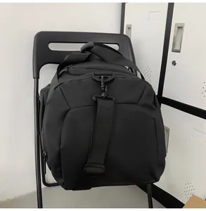 Detail of a black large-capacity gym bag with adjustable strap hanging on a chair