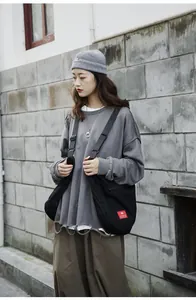 Detail view of a black large-capacity canvas crossbody bag with nylon strap and red logo