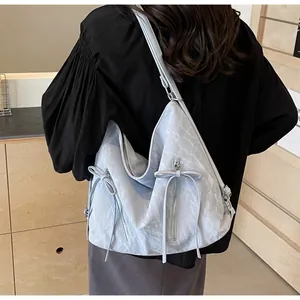 Detail of light blue wrinkled texture shoulder bag with bow zippers on model's back