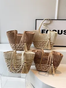 Juego de cuatro bolsos tote de paja bohemios con borlas de madera en soporte de exhibición