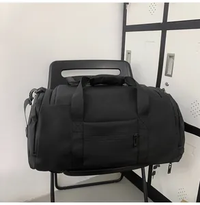 Close-up of a black gym duffel bag with dual handles on a chair in a locker room setting