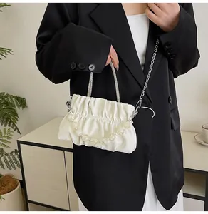 Detail of white pleated cloud bag with pearl chain strap and rhinestone handle accents