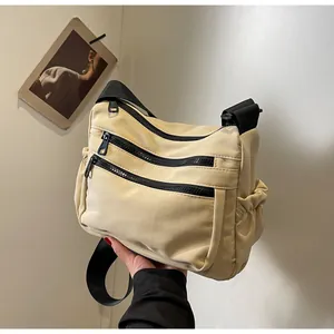 Detail of nylon shoulder bag with triple black zippers and adjustable drawstring pockets