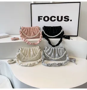 Detail of ruched cloud bags with elegant pearl handles and pleated straps in various colors