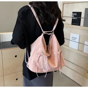 Detail of pink crinkled patent leather backpack with bow ribbons and metal zippers