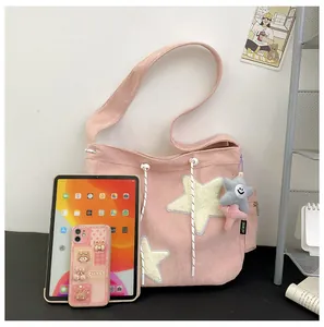 Gros plan du sac cabas en velours côtelé rose avec écussons étoiles et breloques