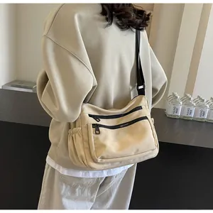 Detail view of the beige nylon crossbody bag featuring black zippers and side pockets
