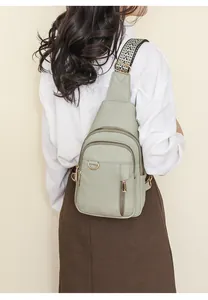 Detail view of light green crossbody bag with lychee grain texture and jacquard strap