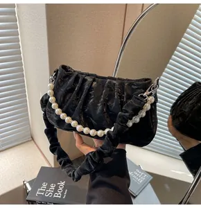 Close-up of black pleated cloud bag featuring large pearl handle and metallic clasp detail