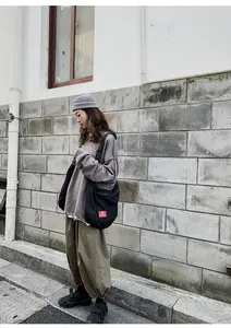 Outdoor street style view of a black canvas crossbody bag with large capacity