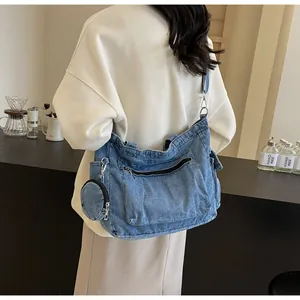 Dettaglio della grande borsa a tracolla in denim con mini portamonete in un caffè