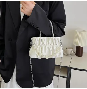 Detail of white pleated cloud bag with acrylic bead handle and silver chain strap